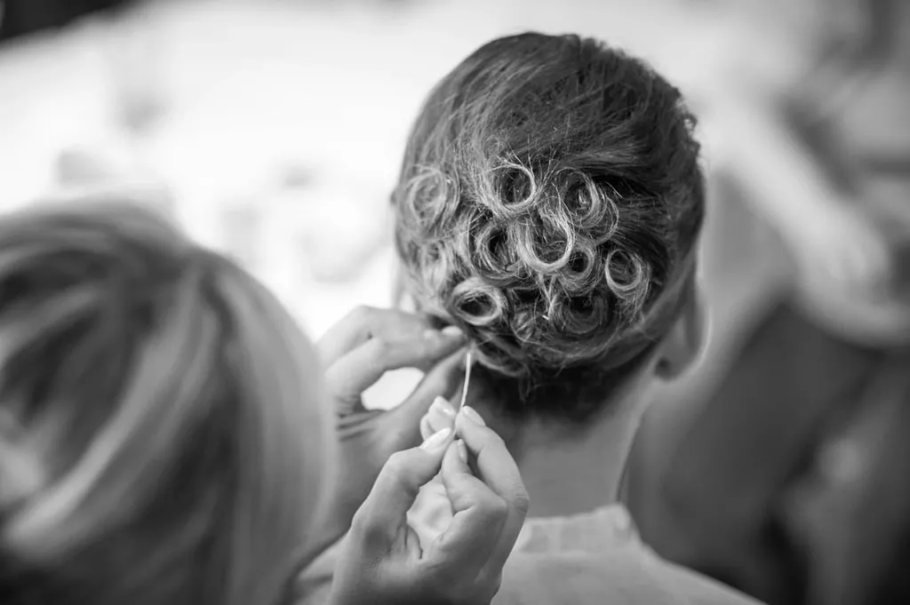 Une coiffeuse termine un chignon bouclé
