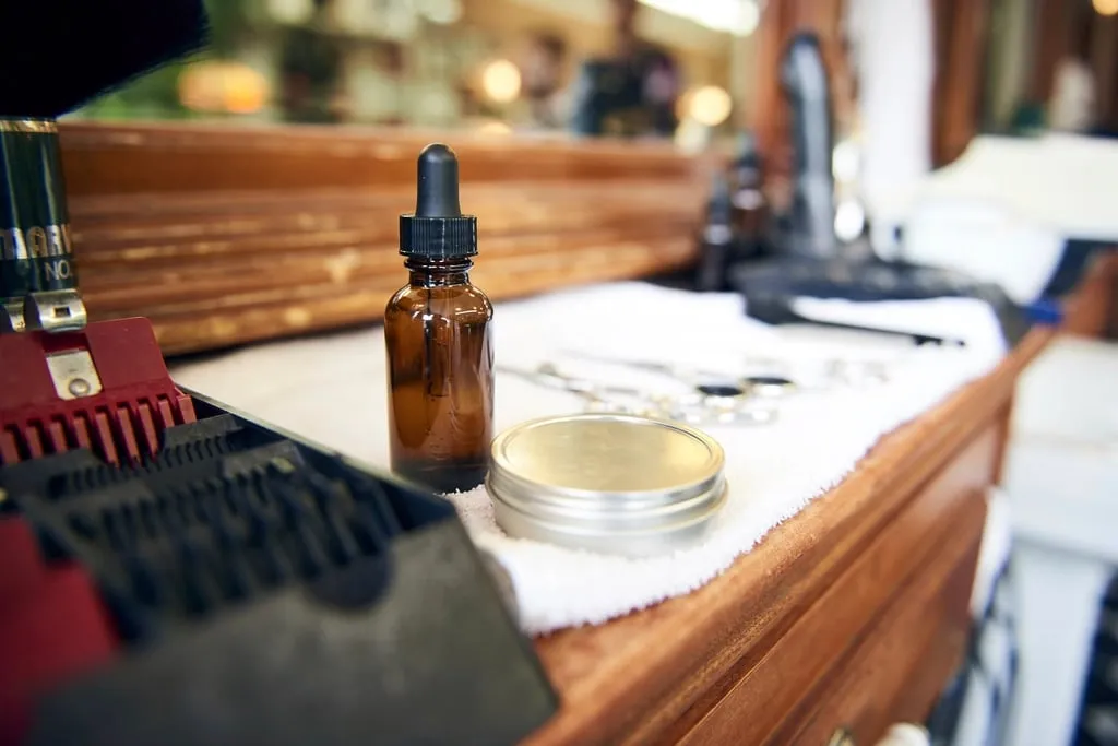 Le poste de travail du salon : flacon d’huile, cire et peignes sur un comptoir en bois