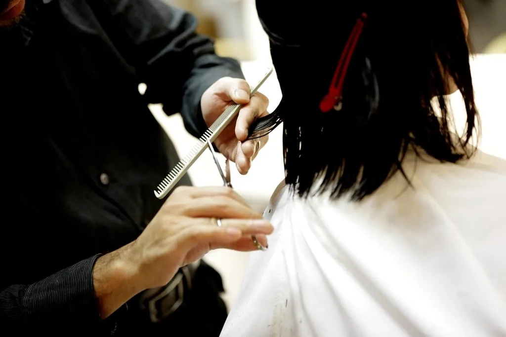 Une coiffeuse coupe les cheveux d’une cliente