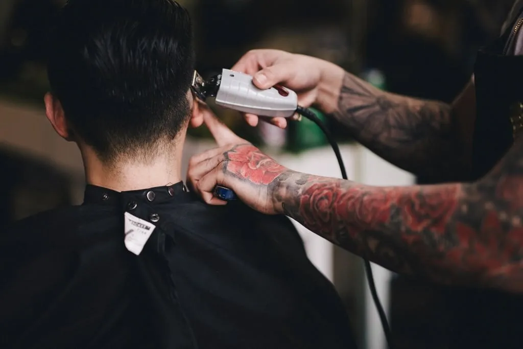 Un coiffeur fait un dégradé à la tondeuse sur la nuque d’un client
